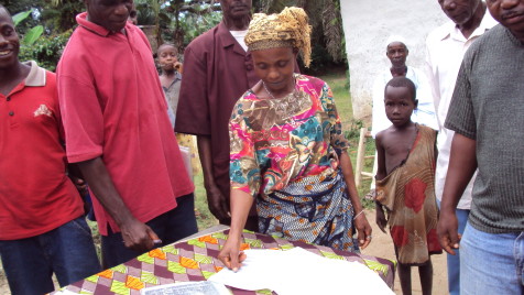 Opens popup gallery with A woman uses her thumbprint to mark her agreement on a memorandum o understanding on how the community will govern its land, Rivercess County, Liberia.