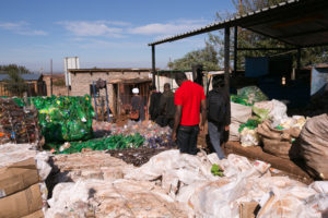 Juves (in red) walks through the recycling that funds a paralegal program in South Africa